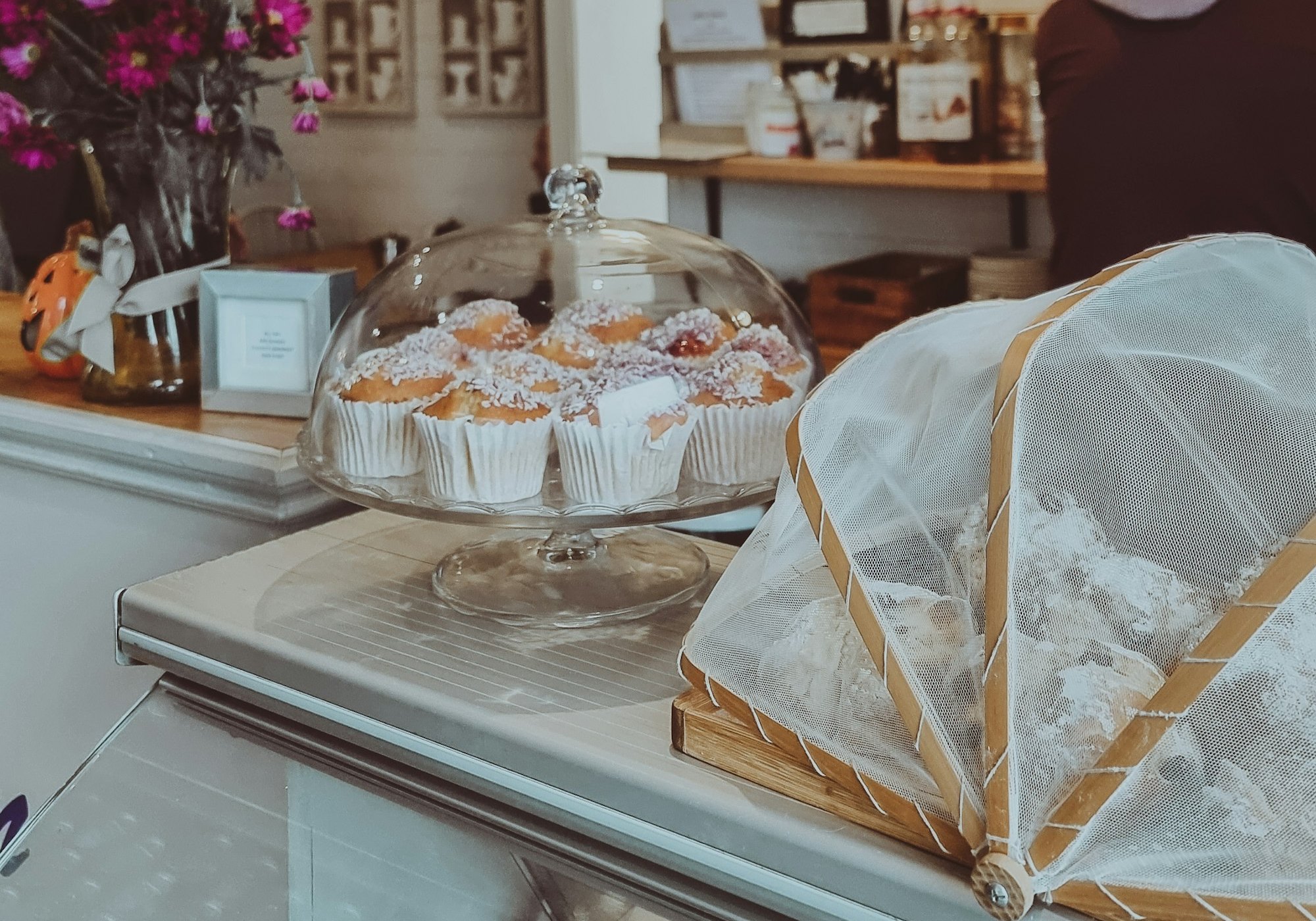 A bakery counter with muffins under a glass dome
