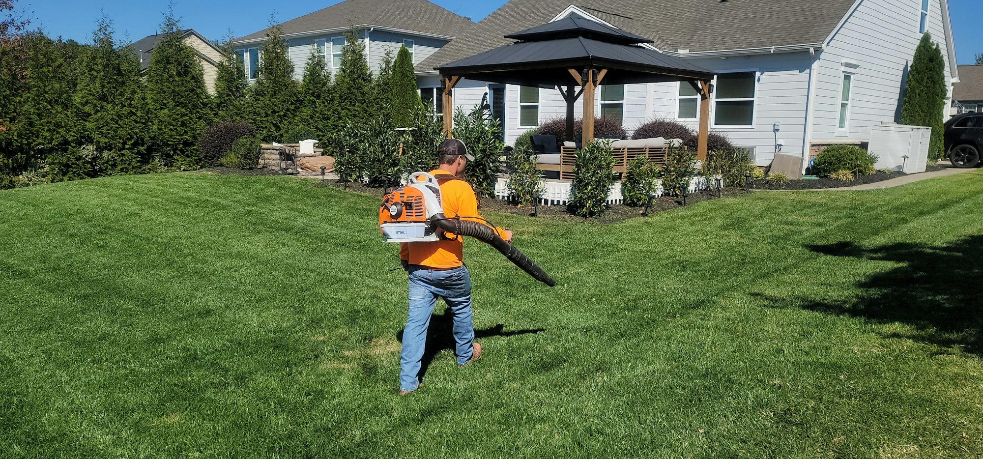 Crew member clearing clippings with a backpack blower after mowing
