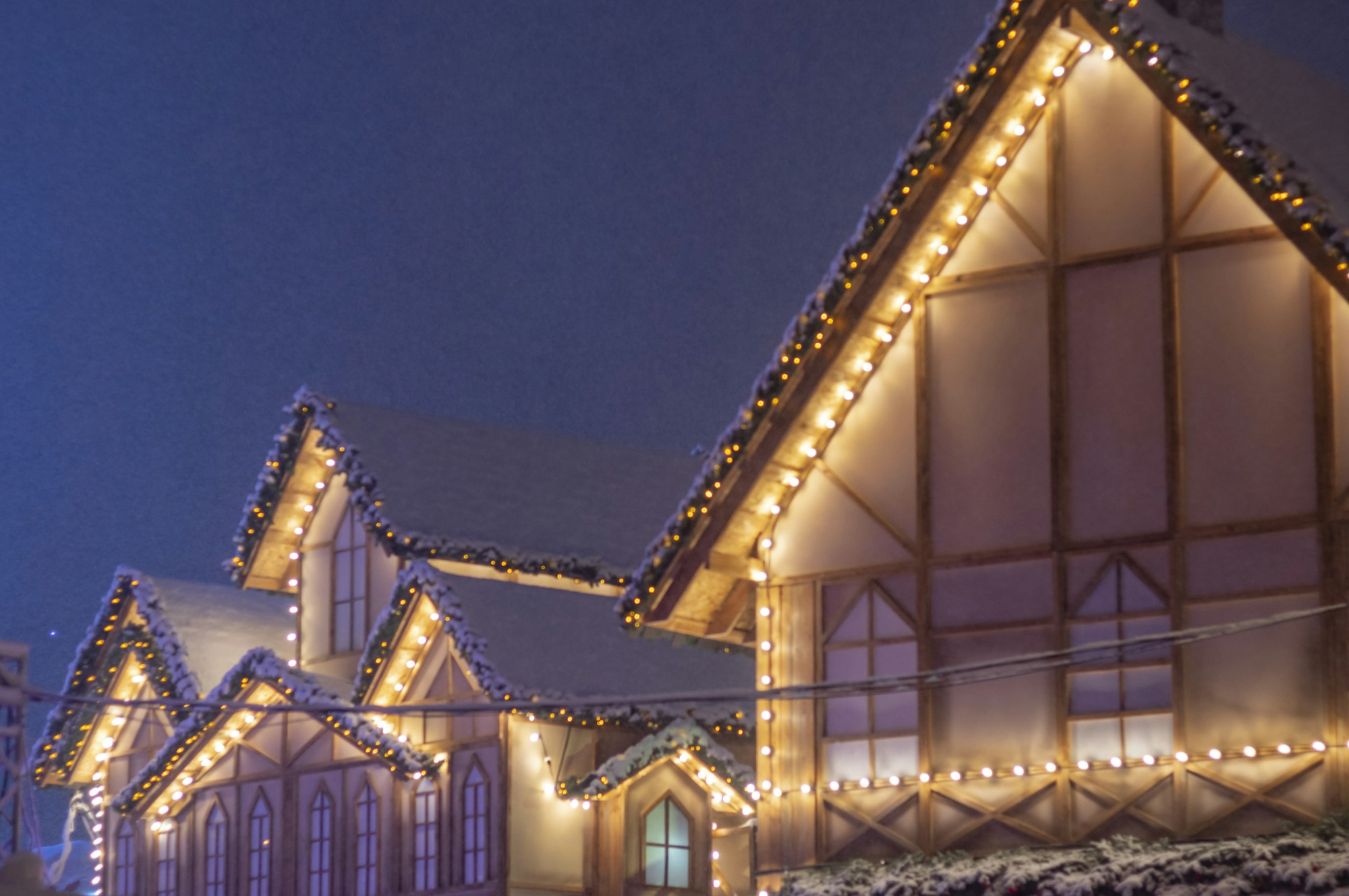 Peaked rooflines lined with warm white lights at dusk